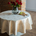 Round table with a beige tablecloth, vase of red roses, and small food items.
