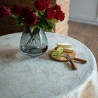 Vase with red roses on a table with a cutting board and kiwi slices.