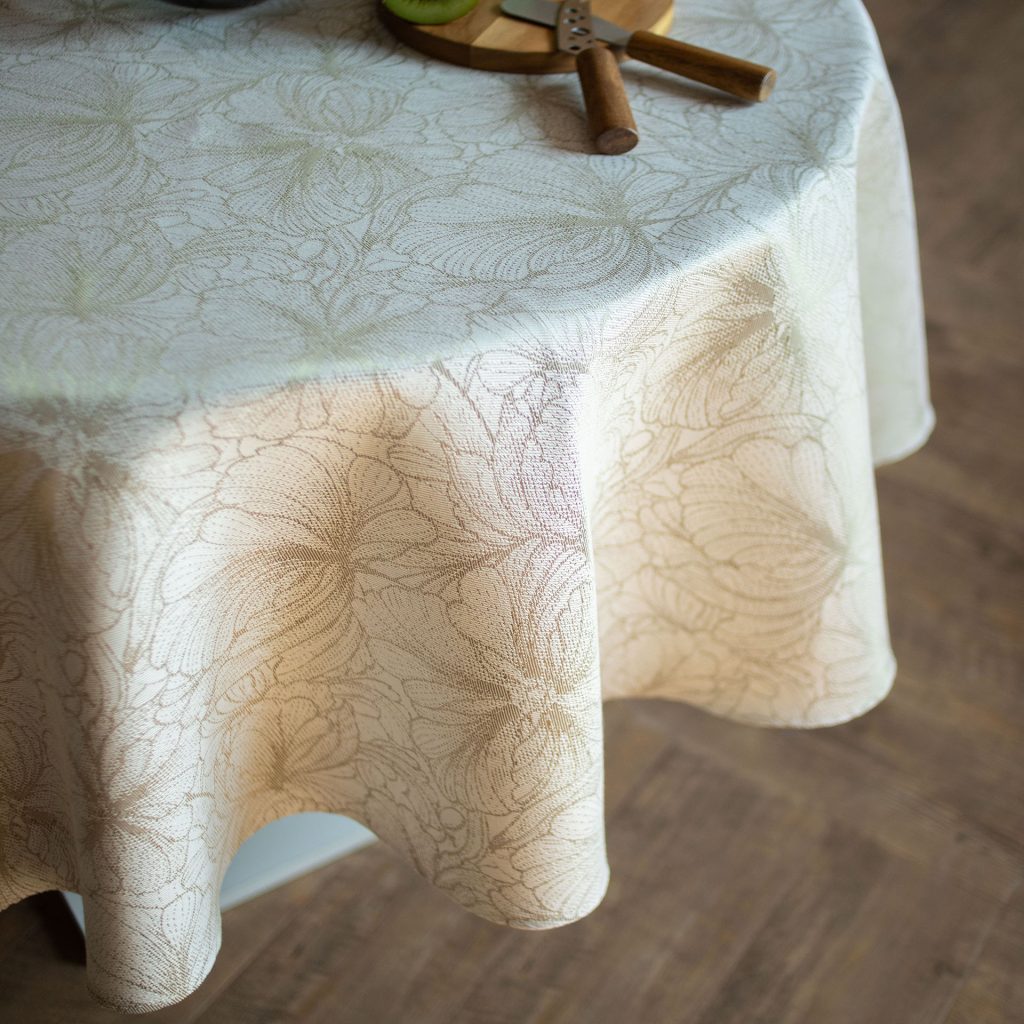 Round table with a floral patterned tablecloth on a wooden floor.