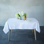 White tablecloth on a wooden table with decorative items against a plain wall.